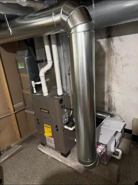 Whole-home dehumidifier installed beside a residential furnace and metal ductwork
